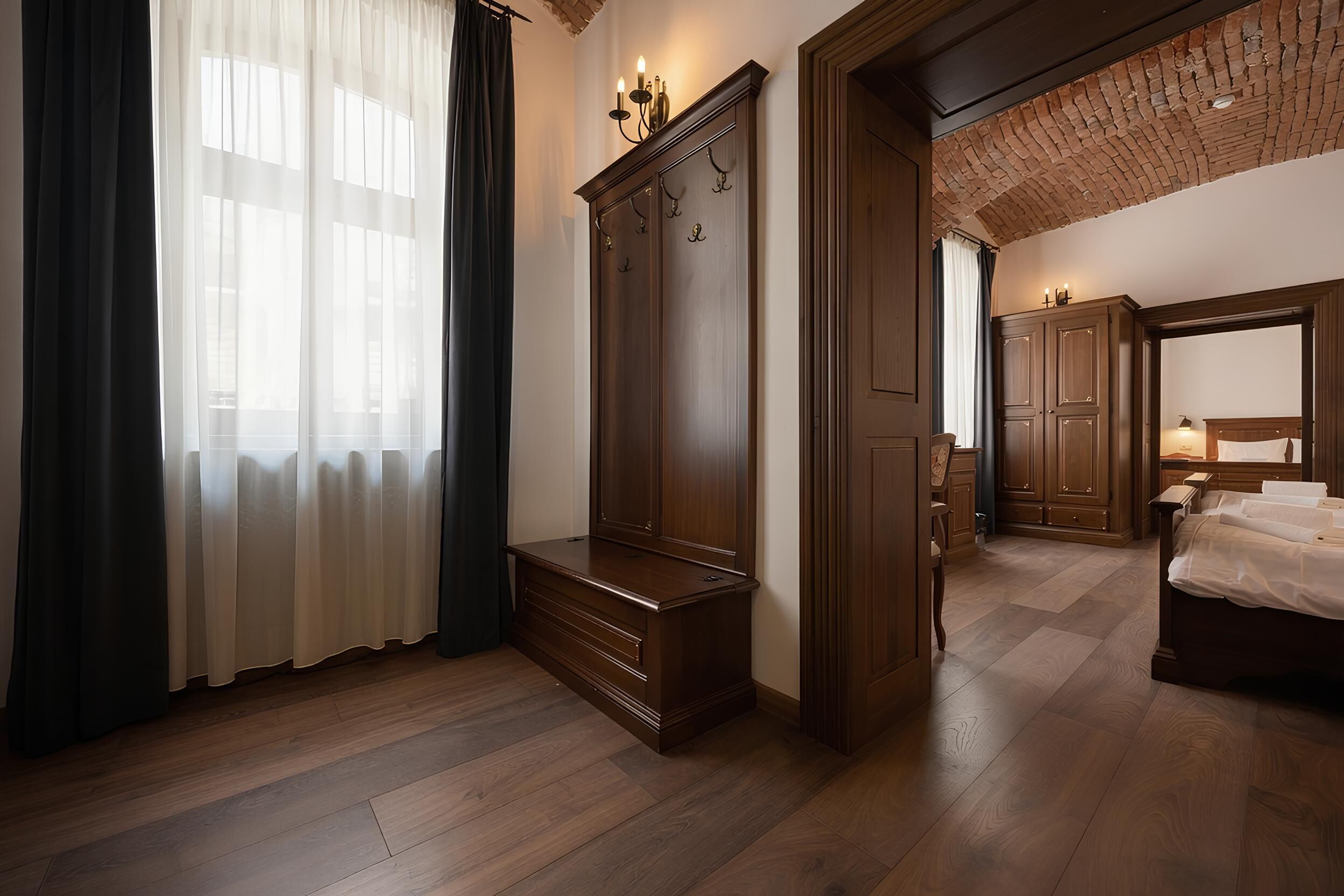 A room with wooden flooring, a bed, a wardrobe, and a bench.