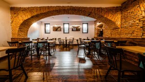 A restaurant with brick arches, wooden tables, and chairs. - Casa Chitic Hotels (Brasov)