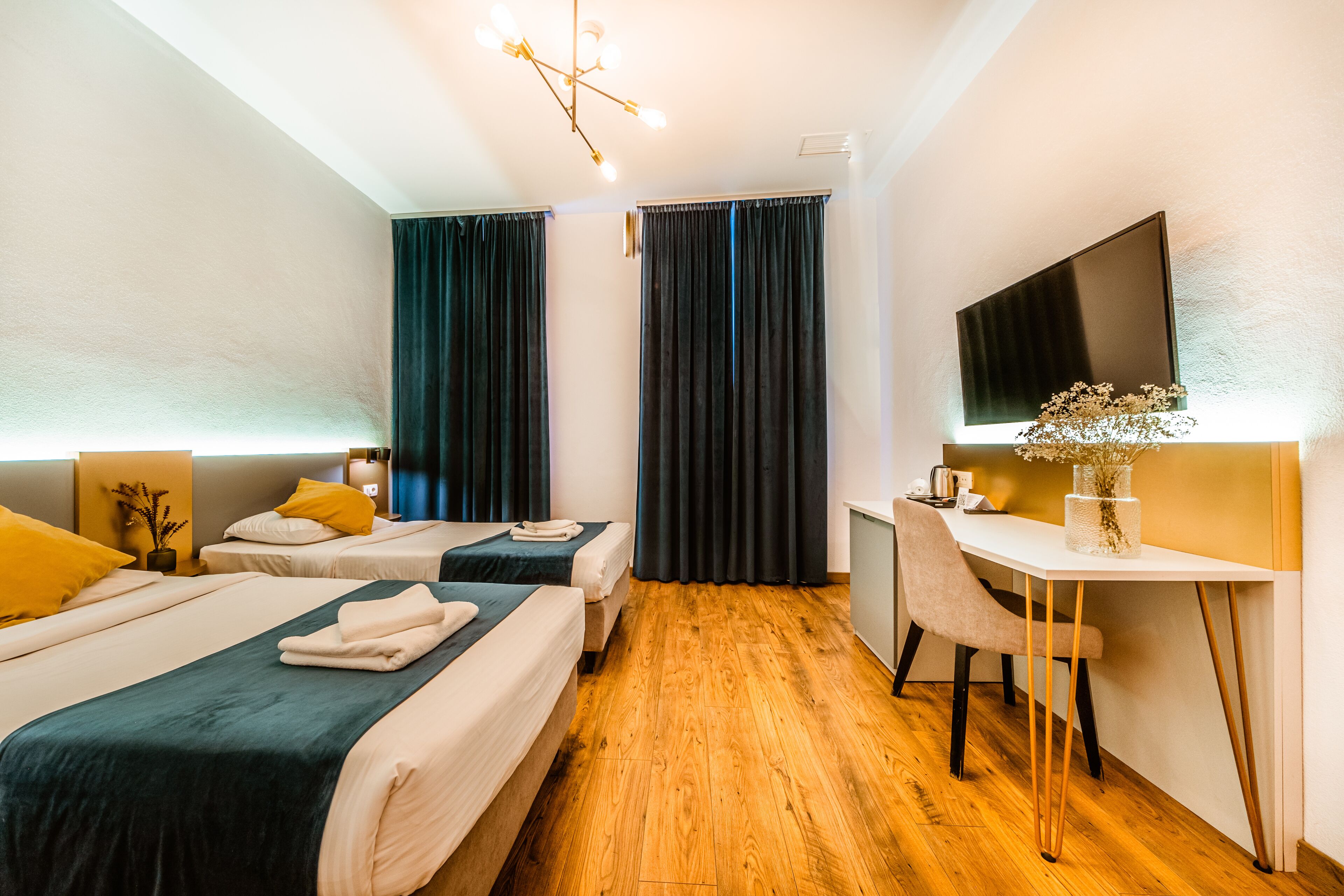 Une chambre d’hôtel avec deux lits, un bureau, une chaise, une télévision et un plancher en bois.