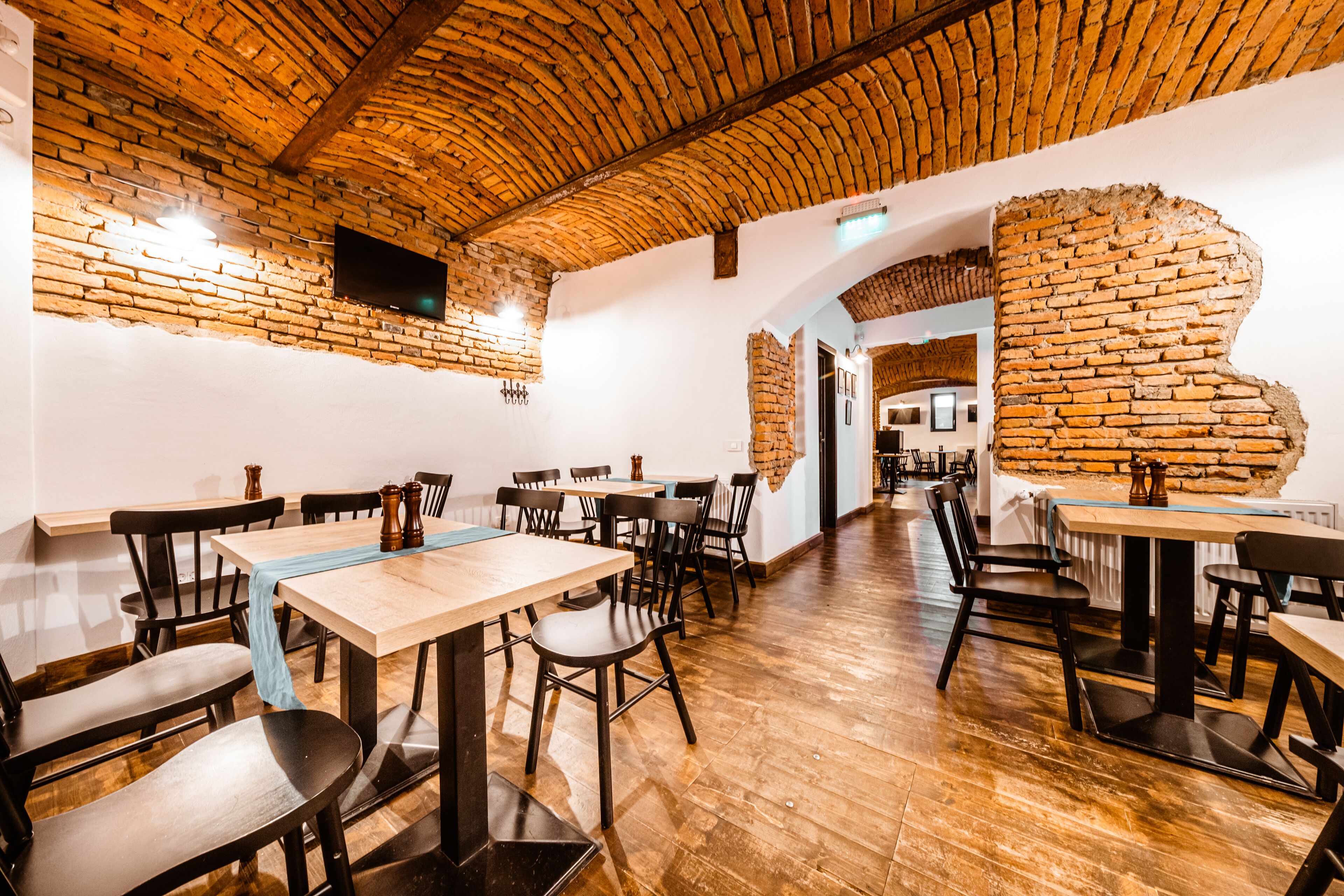 A restaurant with brick walls, wooden tables, and chairs.
