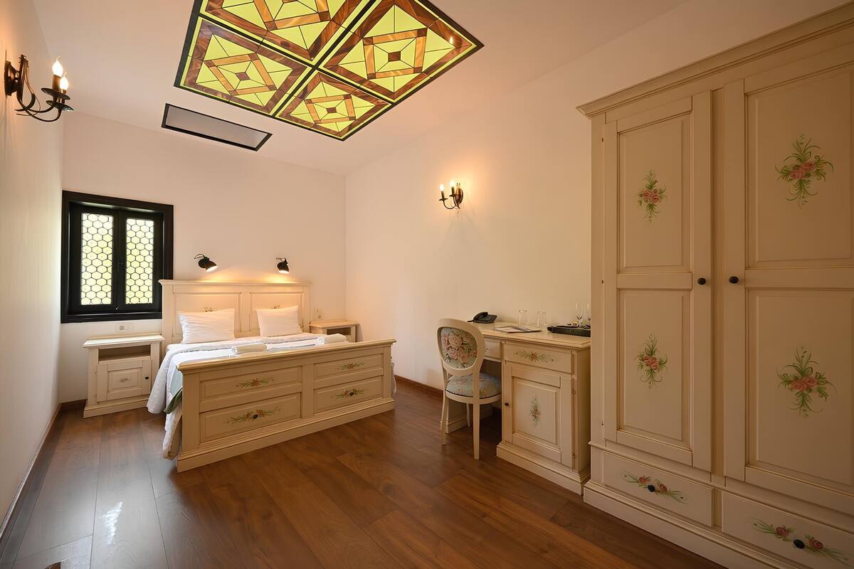 A bedroom with a bed, bedside tables, a desk, a chair, and a wardrobe.