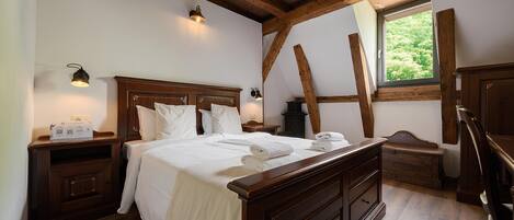 Un dormitorio con cama de madera, mesitas de noche, cómoda y ventana con vistas al verdor.