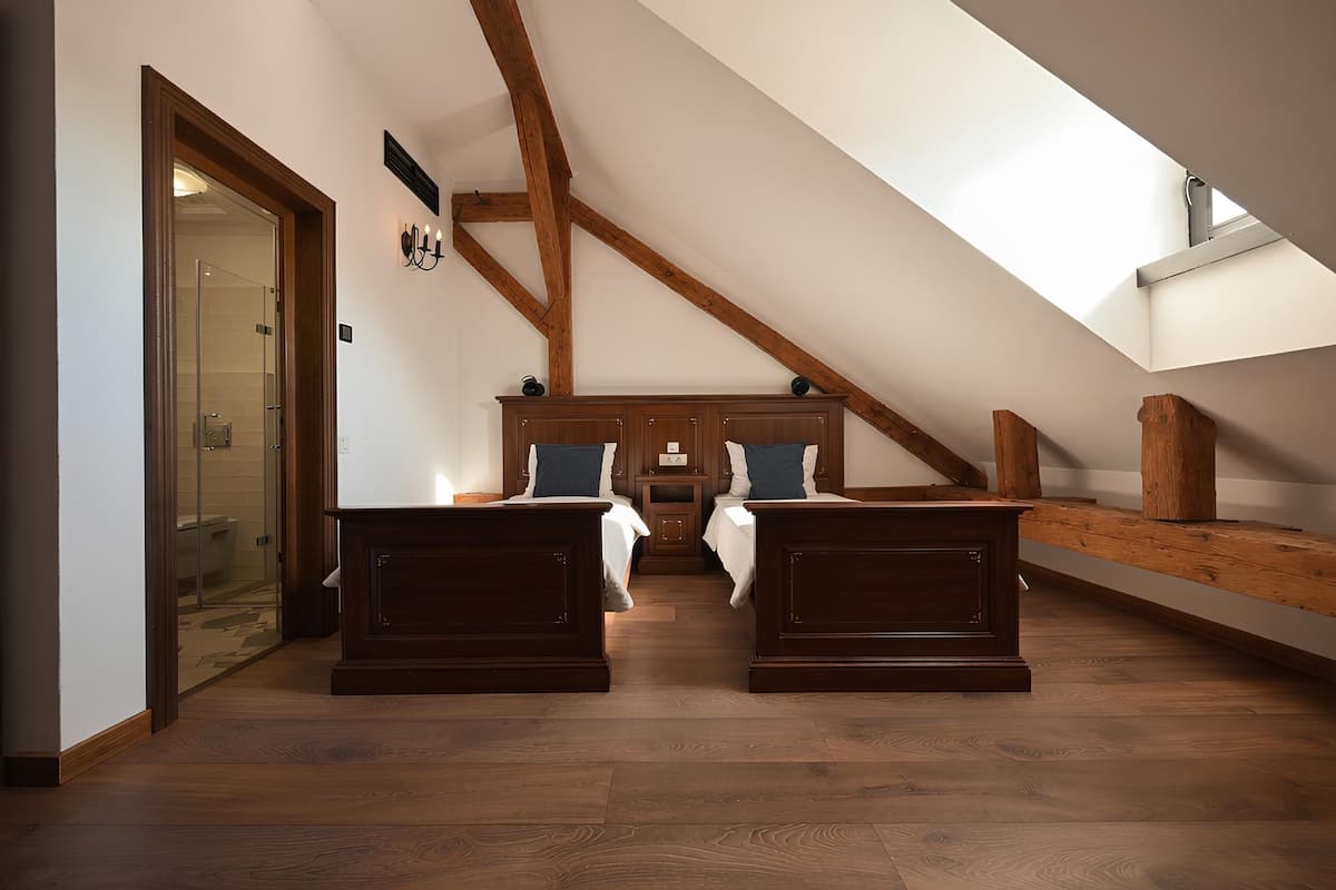 An attic bedroom with wooden beams, a skylight, and a glass shower door.