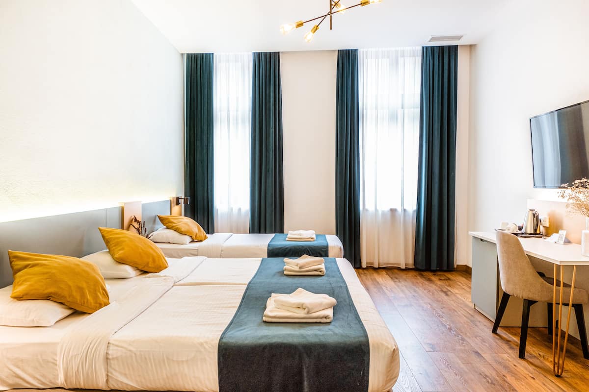 A hotel room with two beds, a desk, and a TV.