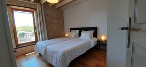 A bedroom with a double bed, a nightstand, a window with curtains, and a door. - A luxurious and cozy vacation home for 6 people on a quiet property. (Azerat)