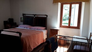 Una camera da letto con un letto a baldacchino, un comodino, una sedia, una finestra vista verde e una scrivania con una sedia.