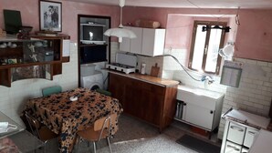 Una cucina compatta con tavolo da pranzo, lavatrice, fornello e frigorifero.