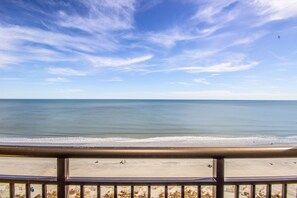 A beach view with a clear sky, calm sea, and a wooden railing in the foreground. - Oceanfront, Modern, Clean, Pools, Hot Tubs, Kids Splash Park, Sleeps 6! (Myrtle Beach)