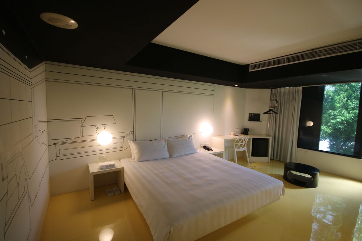 Una habitación de hotel moderna con una cama grande, mesitas de noche, un escritorio y una silla.