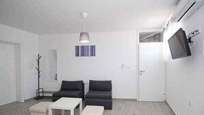 A modern living room with two sofas, a coffee table, and a TV mounted on the wall. - Holiday apartment with air conditioning and internet, near the sea (Baška)