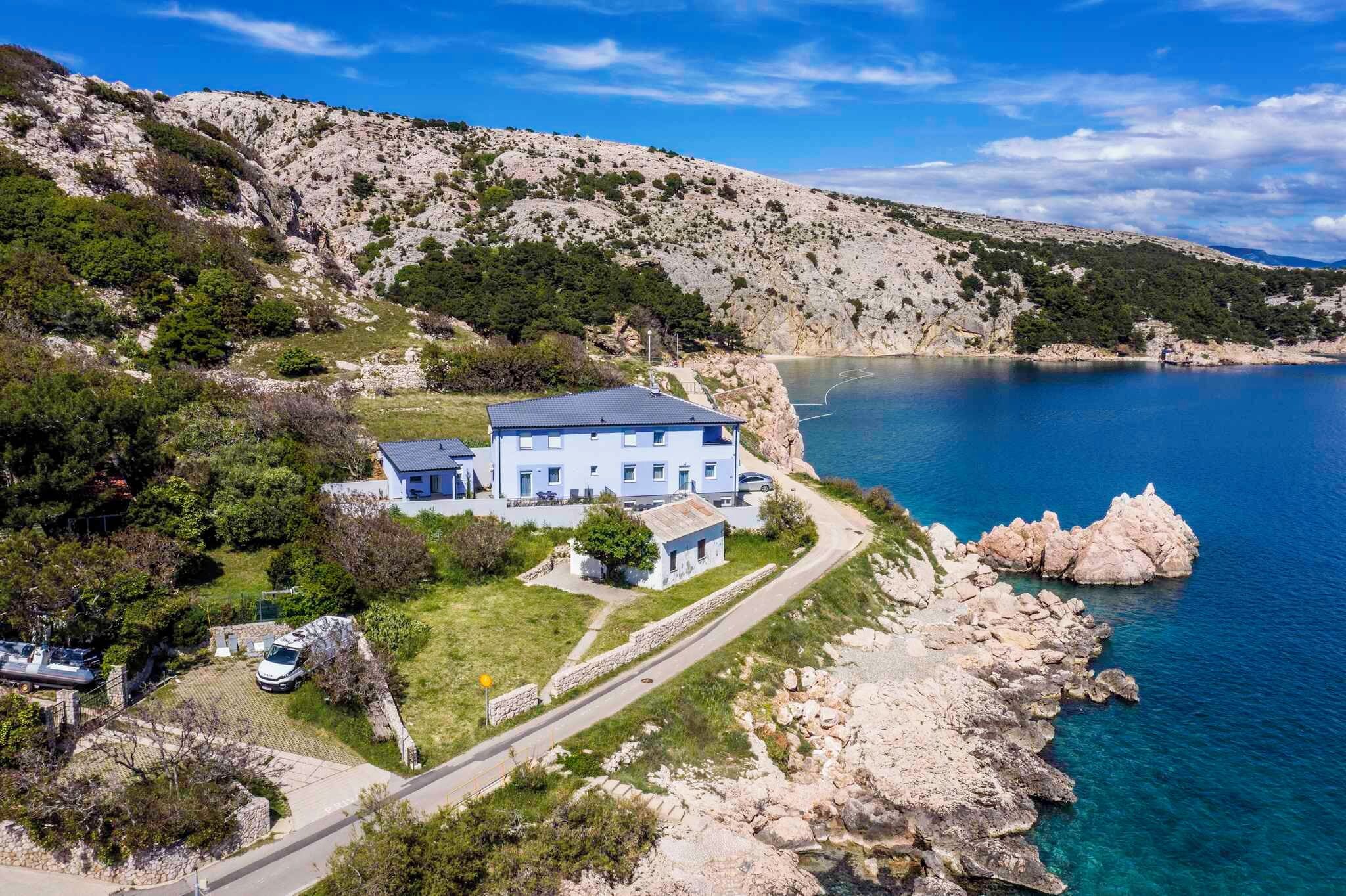 Une propriété située sur la côte, comprenant une grande maison, une allée et un rivage rocheux.