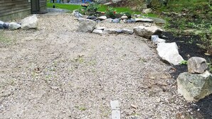 Eine Holzhütte mit einem Schotterweg, der zu einem blauen Stuhl davor führt.