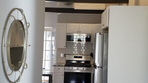 Eine moderne Küche mit Edelstahlgeräten, Holzboden und einem großen Spiegel.