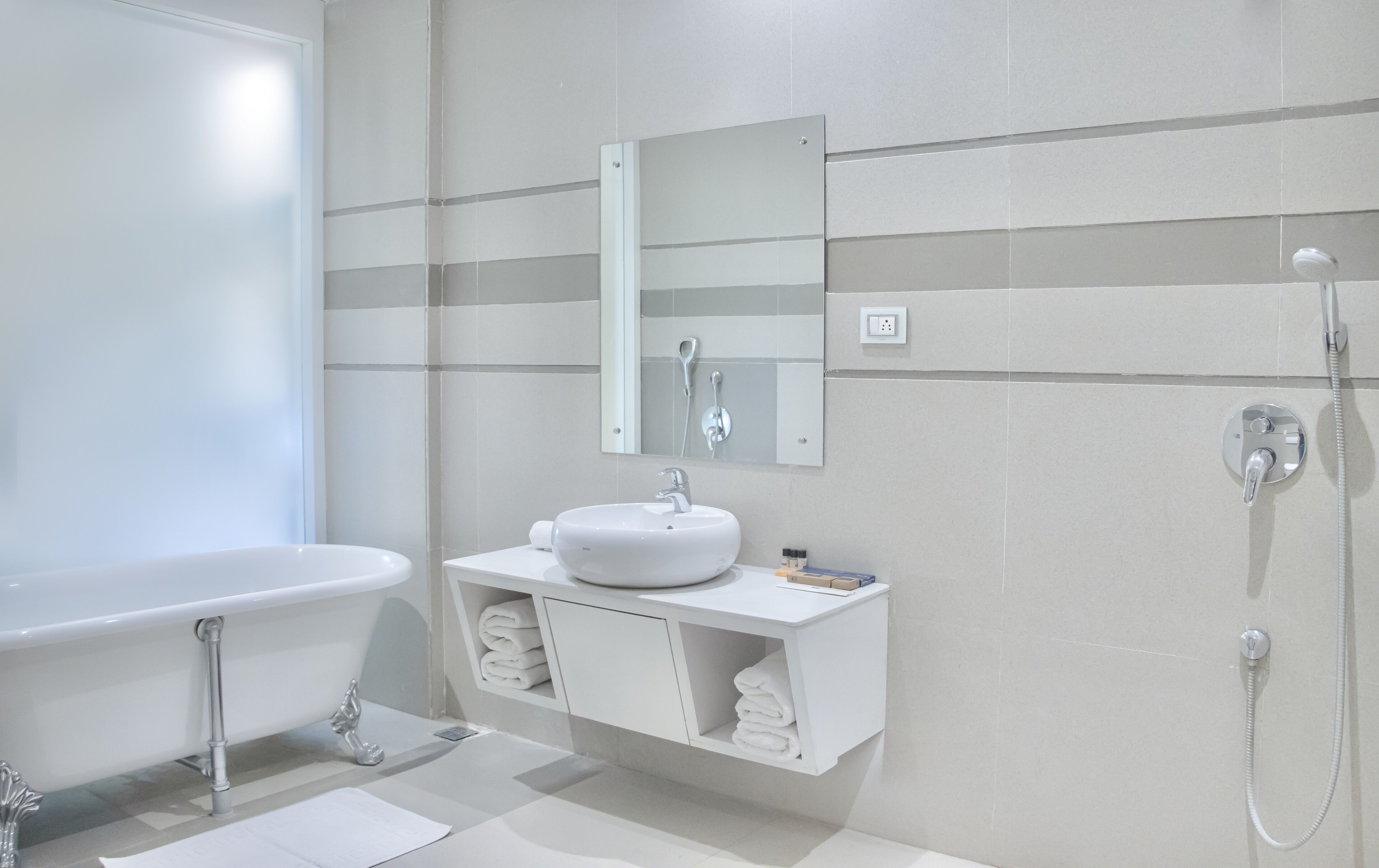 A modern bathroom with a freestanding bathtub, a sink with a mirror above it, and a shower with a handheld showerhead.
