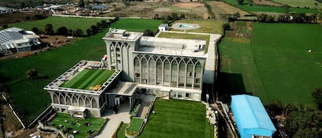 A large, modern building with a prominent entrance and a well-maintained lawn.