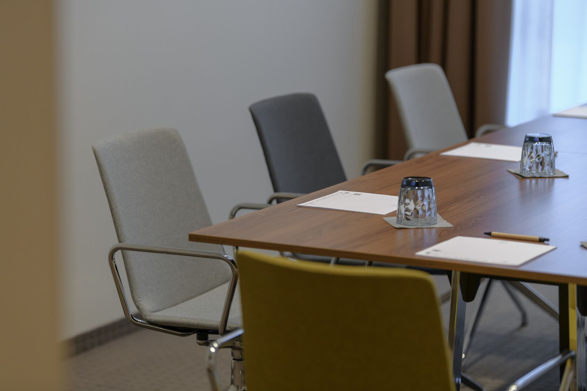 A conference room with a long table, four chairs, and two glass candle holders.