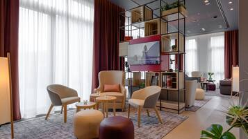 A modern living room with a sofa, armchairs, ottoman, and a TV mounted on a wall.