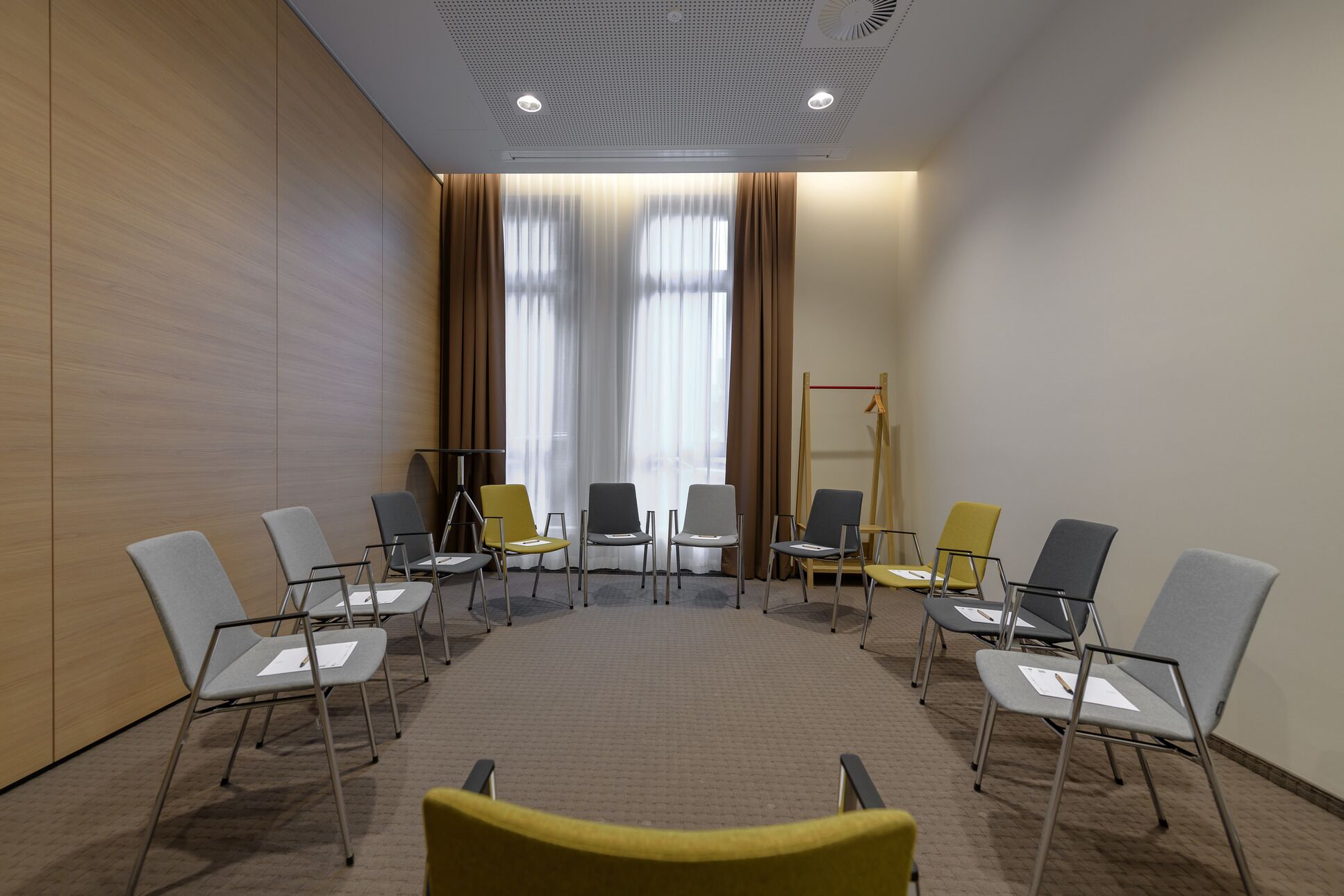 Uma sala de conferências com uma mesa redonda, diversas cadeiras e uma tela de projetor.