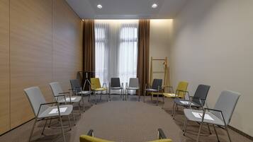 Uma sala de conferências com uma mesa redonda, diversas cadeiras e uma tela de projetor.