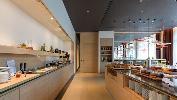 Een moderne ontbijtbar met diverse soorten eten en drinken, houten kastwerk en een helder, goed verlicht interieur.