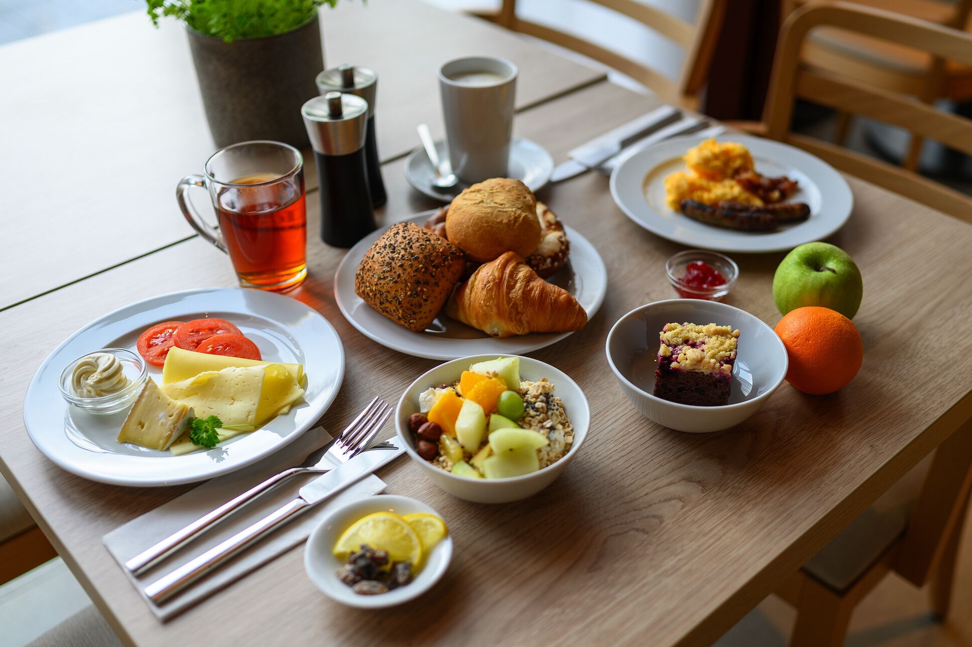 A table set with various breakfast items including croissants, fruit, and a muffin.