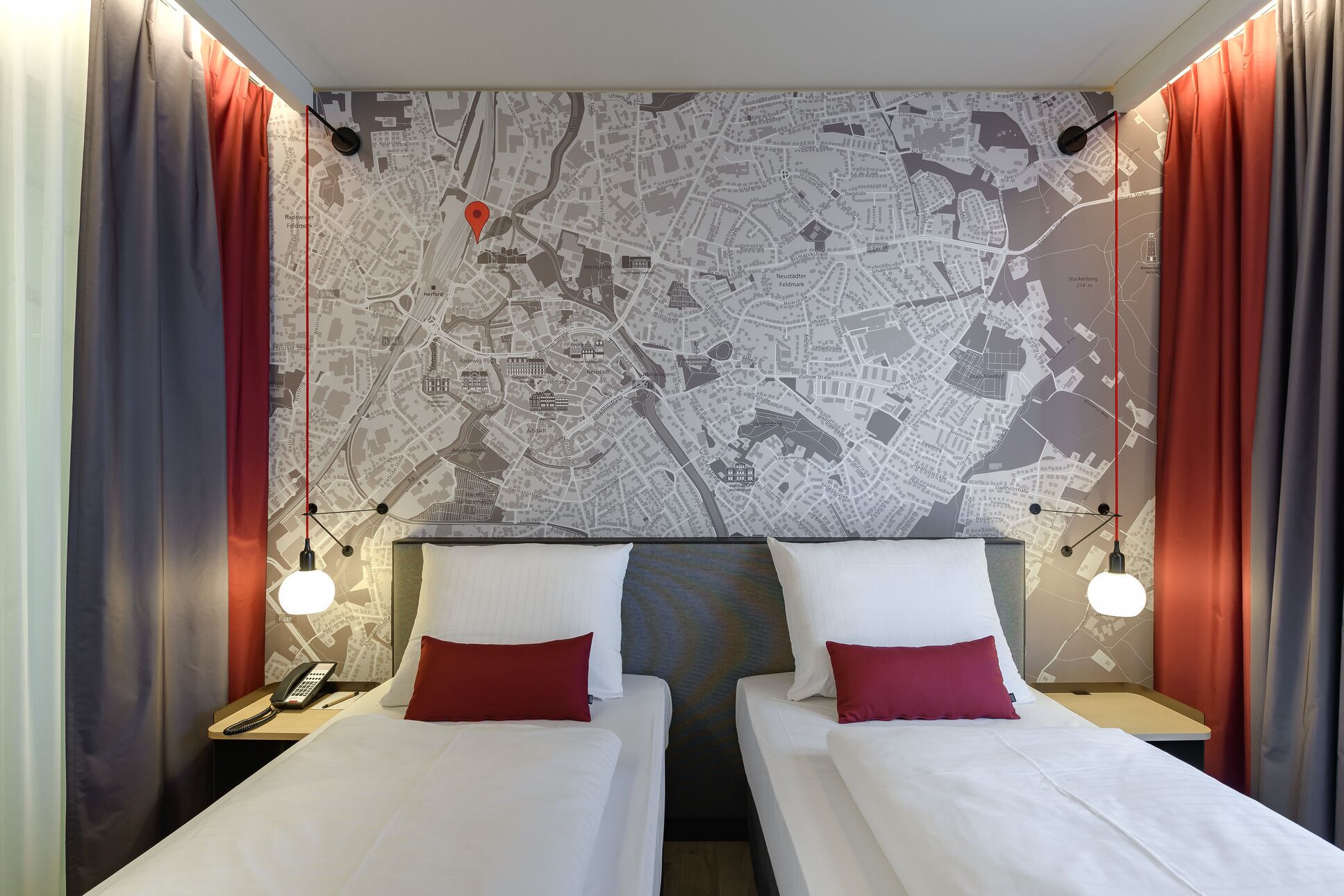 A hotel room with two single beds, a map on the wall, and a telephone on the nightstand.