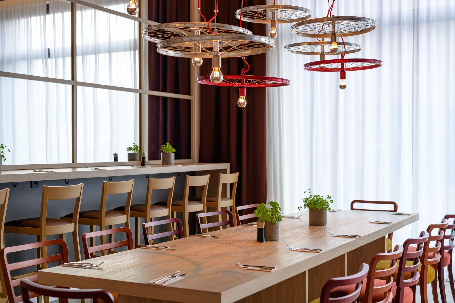 Un comedor moderno con una larga mesa de madera, varias sillas y una lámpara de techo original.
