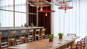 Un comedor moderno con una larga mesa de madera, varias sillas y una lámpara de techo original.