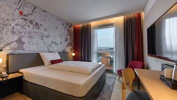 Une chambre d’hôtel avec un grand lit, un bureau, une chaise, une télévision et une carte accrochée au mur.