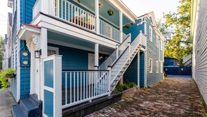 A two-story house with a front porch, a staircase, and a brick pathway. - Charming Downtown 1 BR (Charleston)