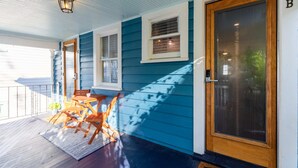 A porch with a wooden door, a window, and a small table with chairs. - Charming Downtown 1 BR (Charleston)