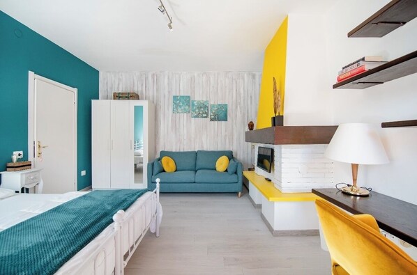 A modern bedroom with a bed, a sofa, a desk, and a TV. - CLUA Holiday House (Porto Ceresio)