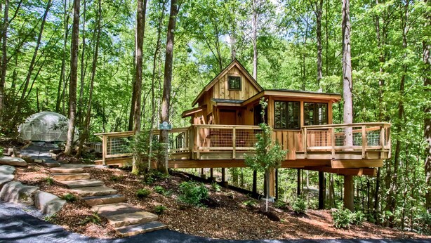 A wooden cabin with a balcony, surrounded by a forest. - Maple Treehouse | Unique, Private, Romantic (Gatlinburg)