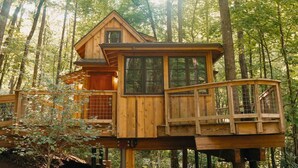 A wooden treehouse with a balcony, surrounded by a forest. - Maple Treehouse | Unique, Private, Romantic (Gatlinburg)