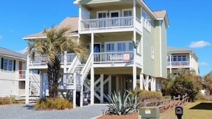 A multi-story building with balconies, a staircase, and a palm tree in the foreground.