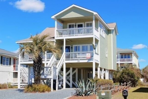 A multi-story building with balconies, a staircase, and a palm tree in the foreground.