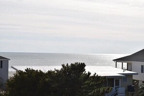 Vista costeira com uma casa e uma praia ao fundo.