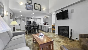A modern living room with a fireplace, a dining area, and a kitchen.