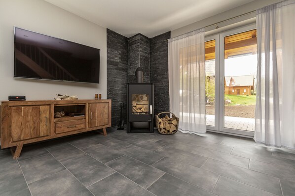 Relax in this stylish living room with a large flat-screen TV, fireplace, and sliding glass door to a garden.