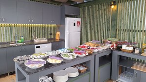 A modern kitchen with grey cabinets, a marble countertop, and a wooden wall. - Ergin Butik Otel (Bozcaada)
