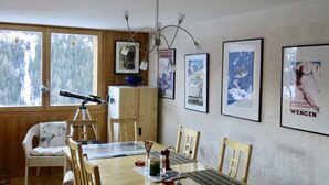 Ein Essbereich mit Holztisch, Stühlen, einem Teleskop und gerahmten Bildern an der Wand.