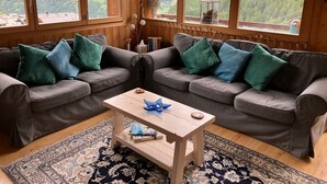 Ein gemütliches Wohnzimmer mit zwei grauen Sofas, einem Holztisch und einem gemusterten Teppich.