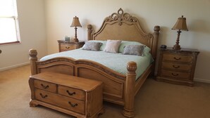 A bedroom with a wooden bed, two nightstands, a dresser, and two lamps.