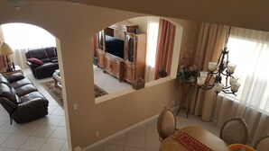 A living room with a sofa, a TV, and a dining area with a table and chairs.