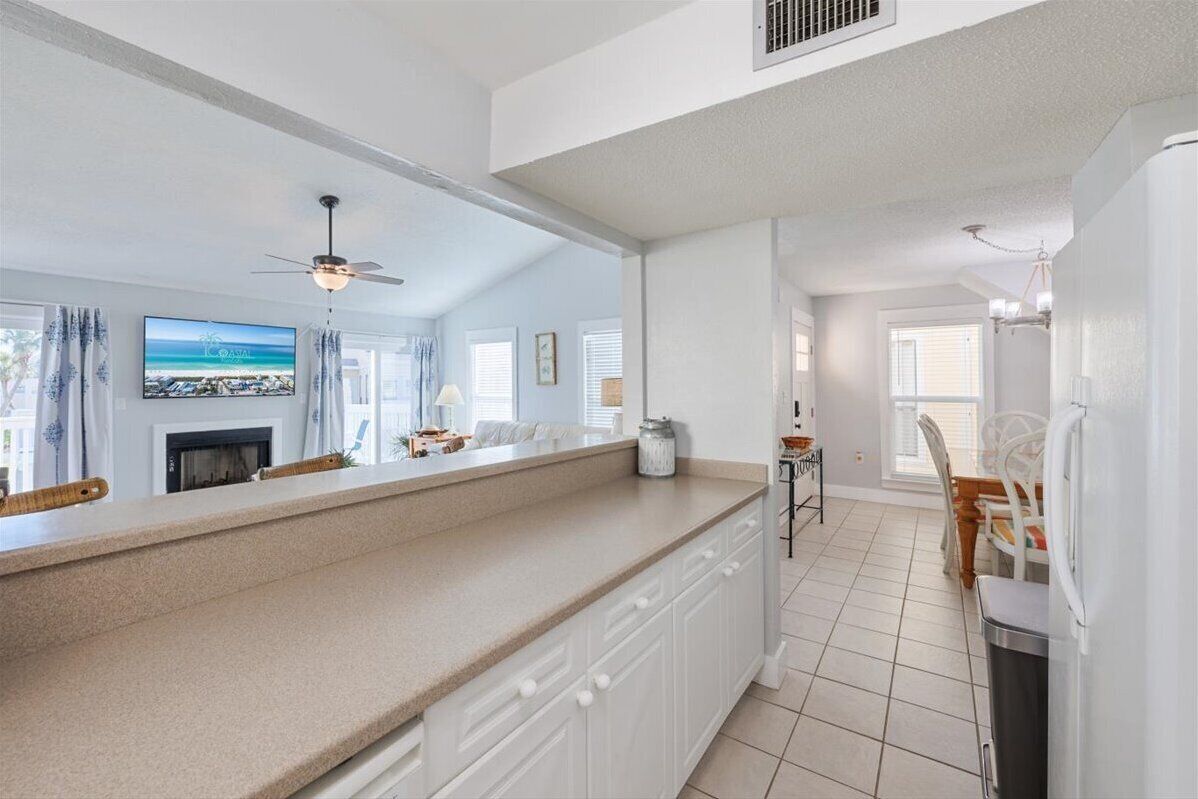 A modern kitchen with a large island, white cabinetry, and a view of the living room. - Private Resort Villa•Beach Service & Golf Cart Included• Boat & Trailer Friendly (Destin)