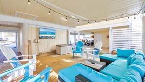 A spacious indoor area with a wooden ceiling, a large window, and a seating area with blue furniture. - Private Resort Villa•Beach Service & Golf Cart Included• Boat & Trailer Friendly (Destin)
