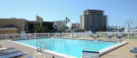 A swimming pool with lounge chairs and a white fence.
