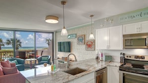 A kitchen with white cabinets, a stainless steel oven, and a large window overlooking the ocean. - Escape to Mayan Princess 213 Beachfront Getaway! (Port Aransas)