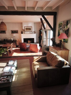 A cozy living room with a fireplace, leather furniture, and a dining area with a table and chairs. - Charming 17th century house on 1 ha of land 4 minutes from Bergerac (Bergerac)