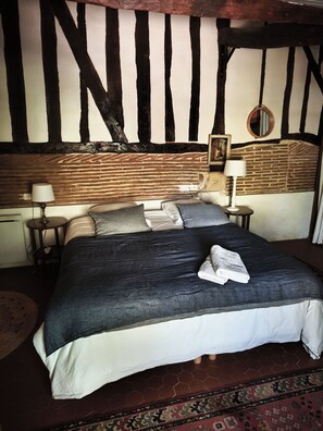 Ein Schlafzimmer mit einem großen Bett, zwei Nachttischen, einem runden Spiegel und einem gemusterten Teppich.